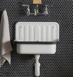 a white sink sitting under a faucet next to a wall mounted soap dispenser