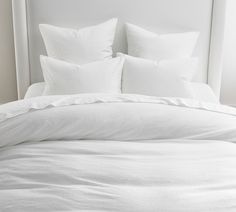 a bed with white sheets and pillows on it