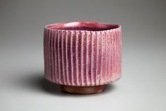 a small pink vase sitting on top of a white table next to a gray wall