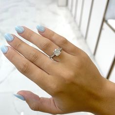 a woman's hand with blue fingernails and a diamond ring on her left hand