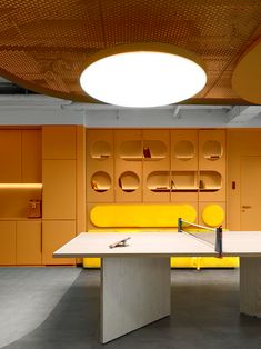 a ping pong table in the middle of a room with orange walls and yellow furniture