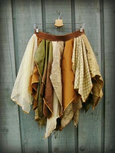 several different colored towels hanging on a clothes line against a wooden wall with a hanger