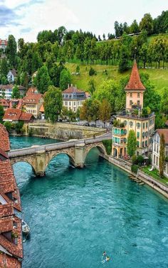 a river running through a lush green hillside next to a bridge over it's water