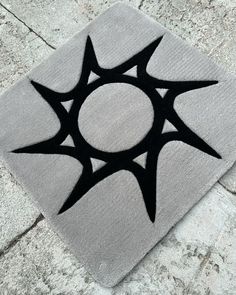 a black and white rug with an abstract design on it's side, in the middle of a stone floor