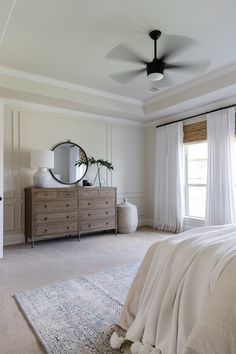 a bedroom with a bed, dresser and large mirror in it's centerpiece