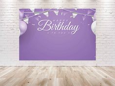 a purple birthday card with balloons and streamers on a white brick wall in an empty room