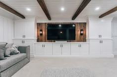 a living room with white cabinets and a flat screen tv mounted on the wall above it