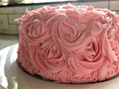 a pink frosted cake sitting on top of a counter