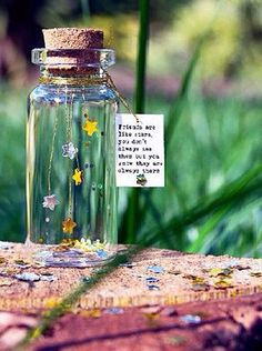 a glass jar filled with flowers sitting on top of a piece of wood next to grass