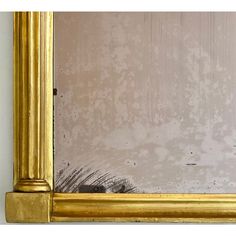 a gold framed mirror sitting on top of a white wall