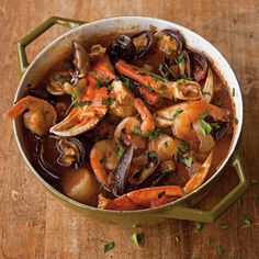 a pot filled with seafood and clams on top of a wooden table