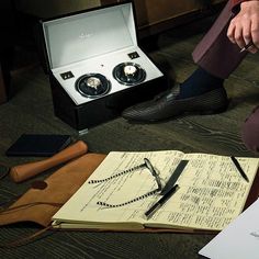 a person sitting on the floor next to an open book with writing and scissors in it