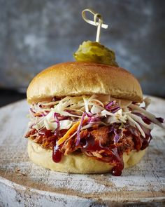 a pulled pork sandwich with coleslaw and pickle slaw on a wooden board