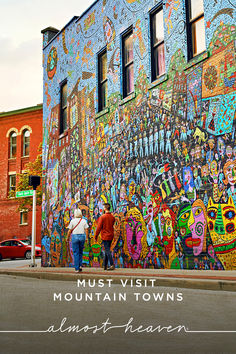 two people walking down the street in front of a mural