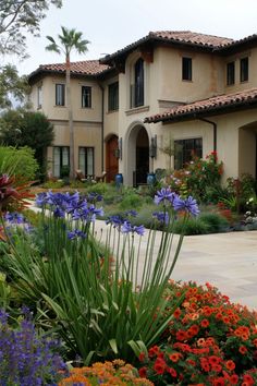 a large house with lots of flowers in the front yard