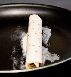 a tortilla in a frying pan with sugar on the side and one rolled up