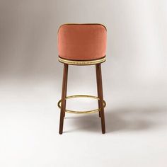 an upholstered bar stool with gold trimmings and a pink velvet seat