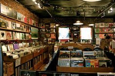 a room filled with lots of books and cds on shelves next to a window covered in lights