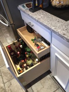 an open drawer in the middle of a kitchen counter filled with bottles and other items