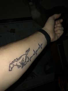 a man's arm with a tattoo on it that has a horse and heartbeat