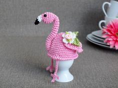 a crocheted pink flamingo hat sitting on top of a white cup