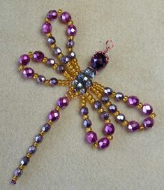 a purple beaded dragon brooch sitting on top of a table