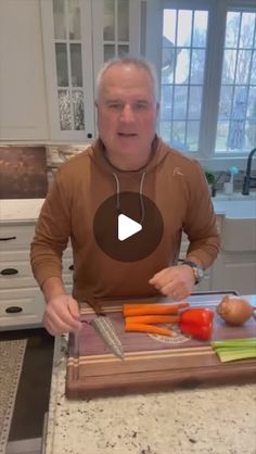 a man standing in front of a cutting board with carrots and celery