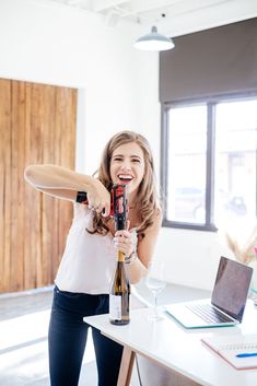 a woman is holding a wine bottle and smiling