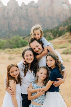 a family posing for a photo in front of mountains and trees with their arms around each other