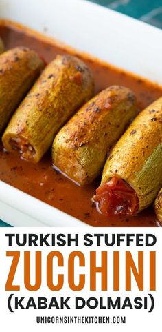 several stuffed zucchini in a white dish with tomato sauce and ketchup