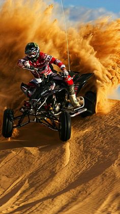 a man riding on the back of a dirt bike in the middle of sand dunes