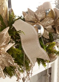 a christmas wreath with gold and silver decorations hanging from it's side on a fireplace mantel