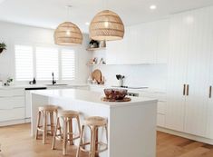 a kitchen with white cabinets and wooden stools next to an island in the middle