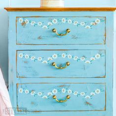 a blue dresser with daisies painted on it