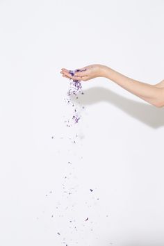 a woman is throwing confetti into the air with her hand and arm outstretched