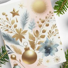 a christmas card with gold ornaments and greenery on it, surrounded by pine branches