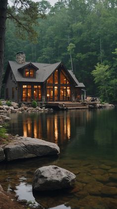 a house sitting on top of a lake next to a forest filled with lots of trees