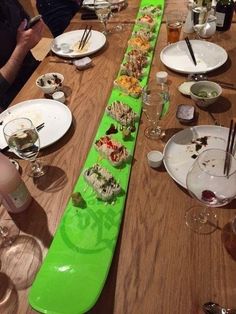 a long table is set with plates and wine glasses on it, along with sushi dishes