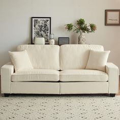 a white couch sitting on top of a wooden floor next to a vase filled with flowers