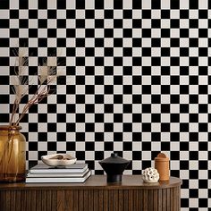 a black and white checkered wallpaper with vases on the table next to it