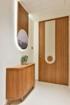 a wooden cabinet sitting in the middle of a room next to a mirror and door