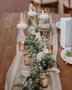 the table is set with candles, flowers and greenery for an elegant wedding reception