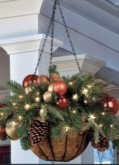 a hanging basket filled with christmas ornaments and pineconis on a porch or porch