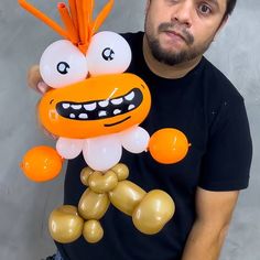 a man holding an orange and white balloon with a face on it's head