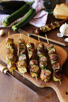 several skewered food items are on a wooden platter next to other foods