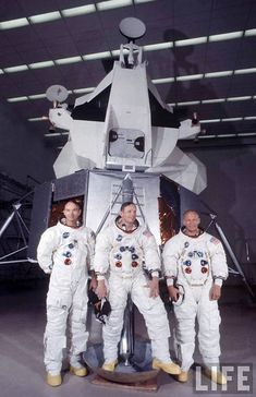 three men in white spacesuits standing next to an object