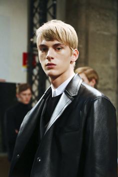 a young man with blonde hair wearing a black leather jacket