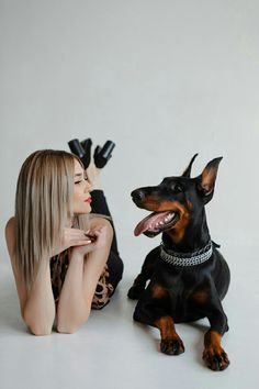 a woman laying on the ground next to a black and brown dog with its tongue out