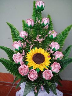 a vase filled with lots of pink roses and green leaves on top of a table