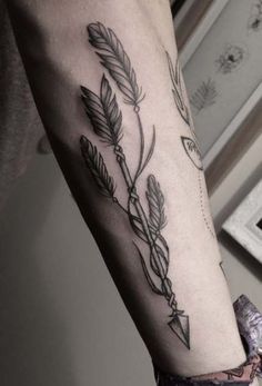 a person with a tattoo on their arm that has arrows and leaves coming out of it